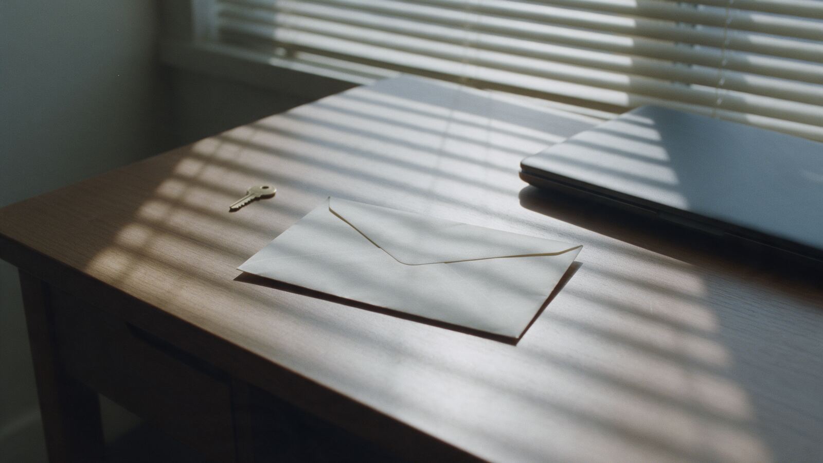 Zalepená obálka vedle zavřeného notebooku a klíčku