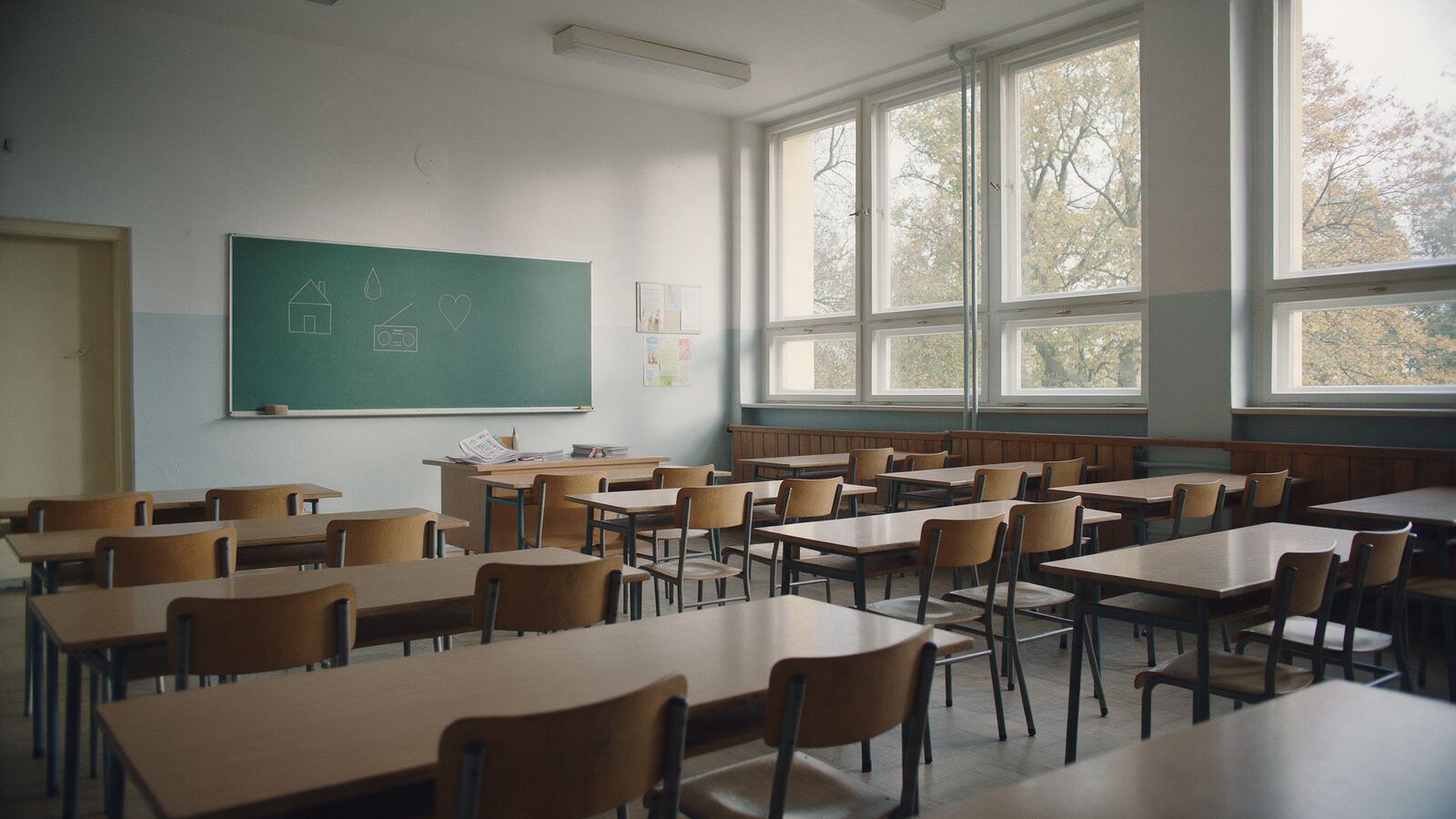 Prázdná třída s lavicemi a tabulí s piktogramy